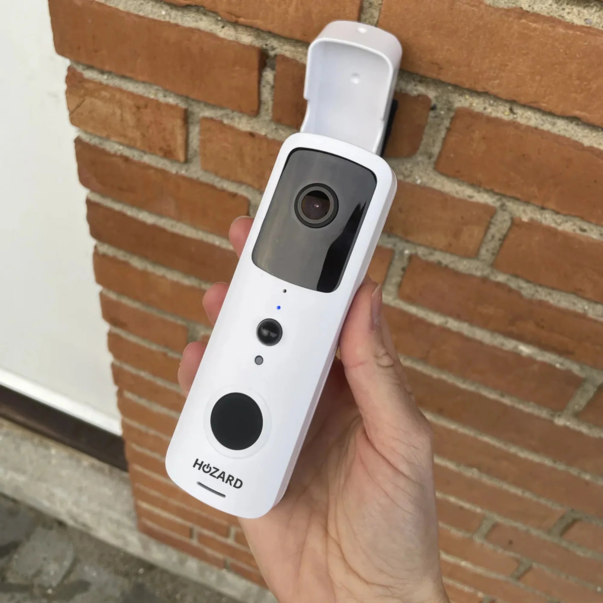 Smart trådlös videodörrklocka med kamera hålls framför tegelvägg, säkerhetslösning